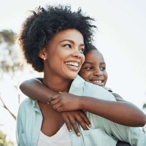 Teen girl hugging younger sibling smiling outdoors | Kania and Khan Orthodontics in Asheboro, NC