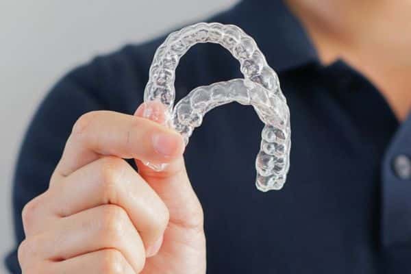Patient holding clear Invisalign aligner tray in Asheboro, NC